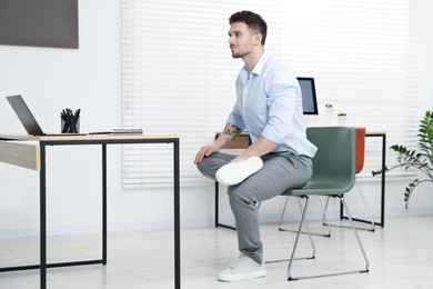 Photo of Handsome man exercising with chair in office