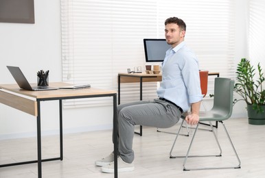 Photo of Handsome man exercising with chair in office