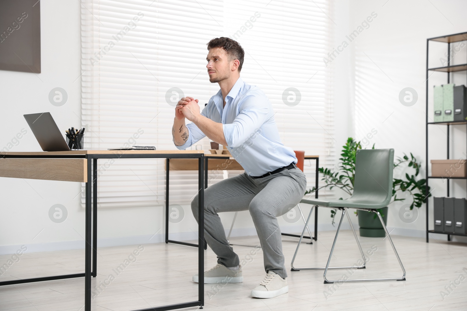 Handsome man doing exercise near desk in office Photo of Handsome man doing exercise near desk in office