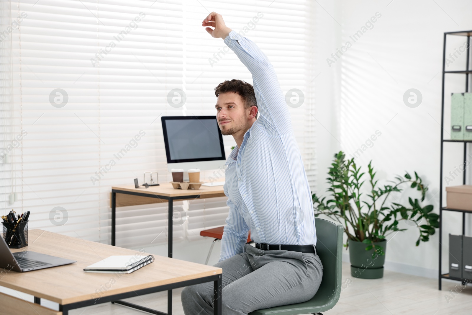 Handsome man stretching on chair in office Photo of Handsome man stretching on chair in office