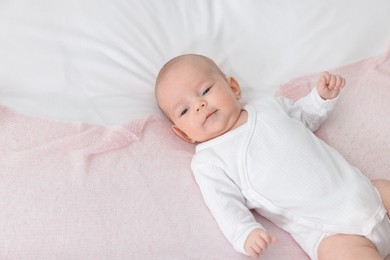 Photo of Cute little baby lying on bed at home, top view. Space for text