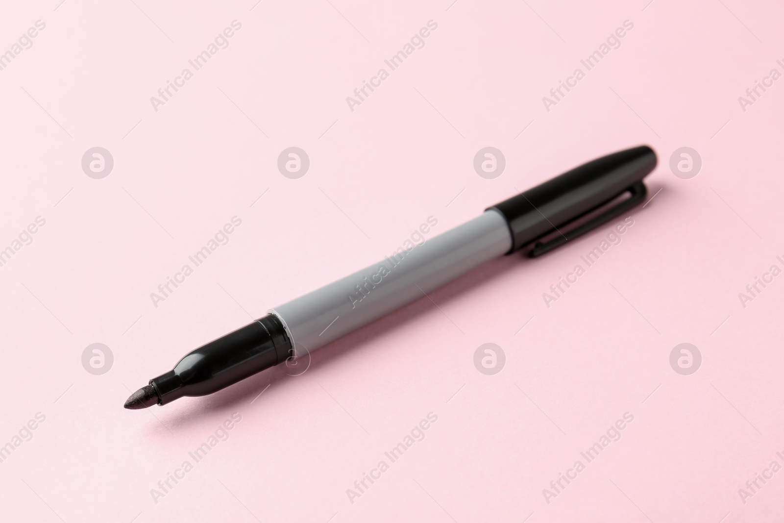 One black marker on light pink background, closeup. Space for text Photo of One black marker on light pink background, closeup. Space for text