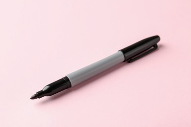 Photo of One black marker on light pink background, closeup. Space for text