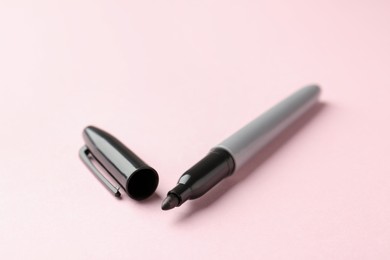 Photo of One black marker on light pink background, closeup. Space for text
