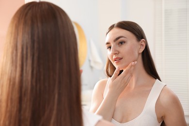Photo of Beautiful woman looking at herself in mirror indoors
