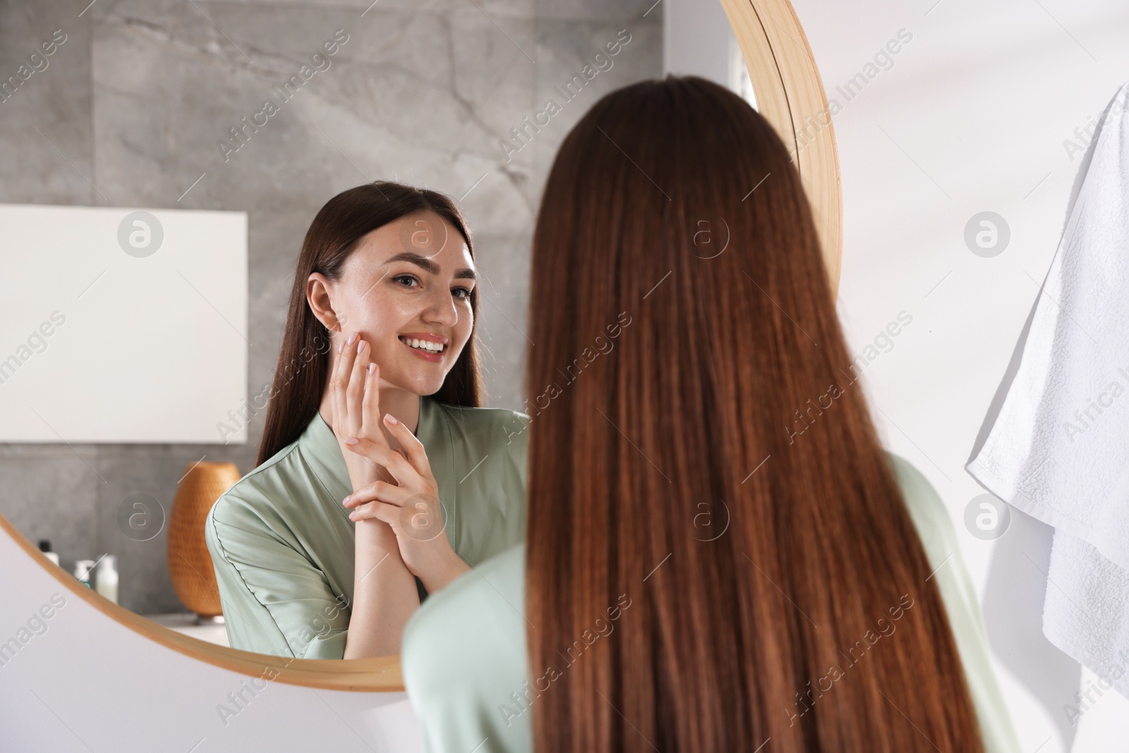 Beautiful woman looking at herself in mirror indoors Photo of Beautiful woman looking at herself in mirror indoors
