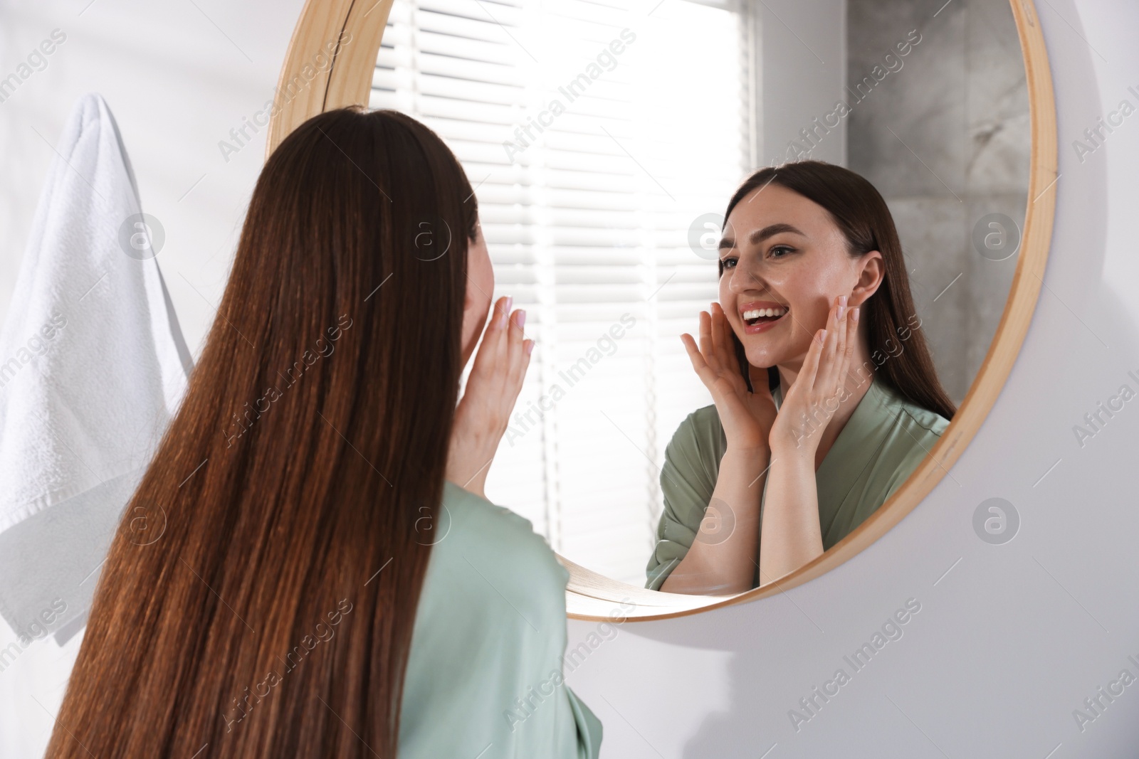 Beautiful woman looking at herself in mirror indoors Photo of Beautiful woman looking at herself in mirror indoors