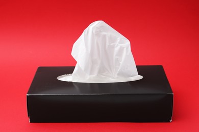 Photo of Box with paper handkerchiefs on red background