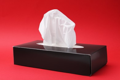 Photo of Box with paper handkerchiefs on red background, closeup