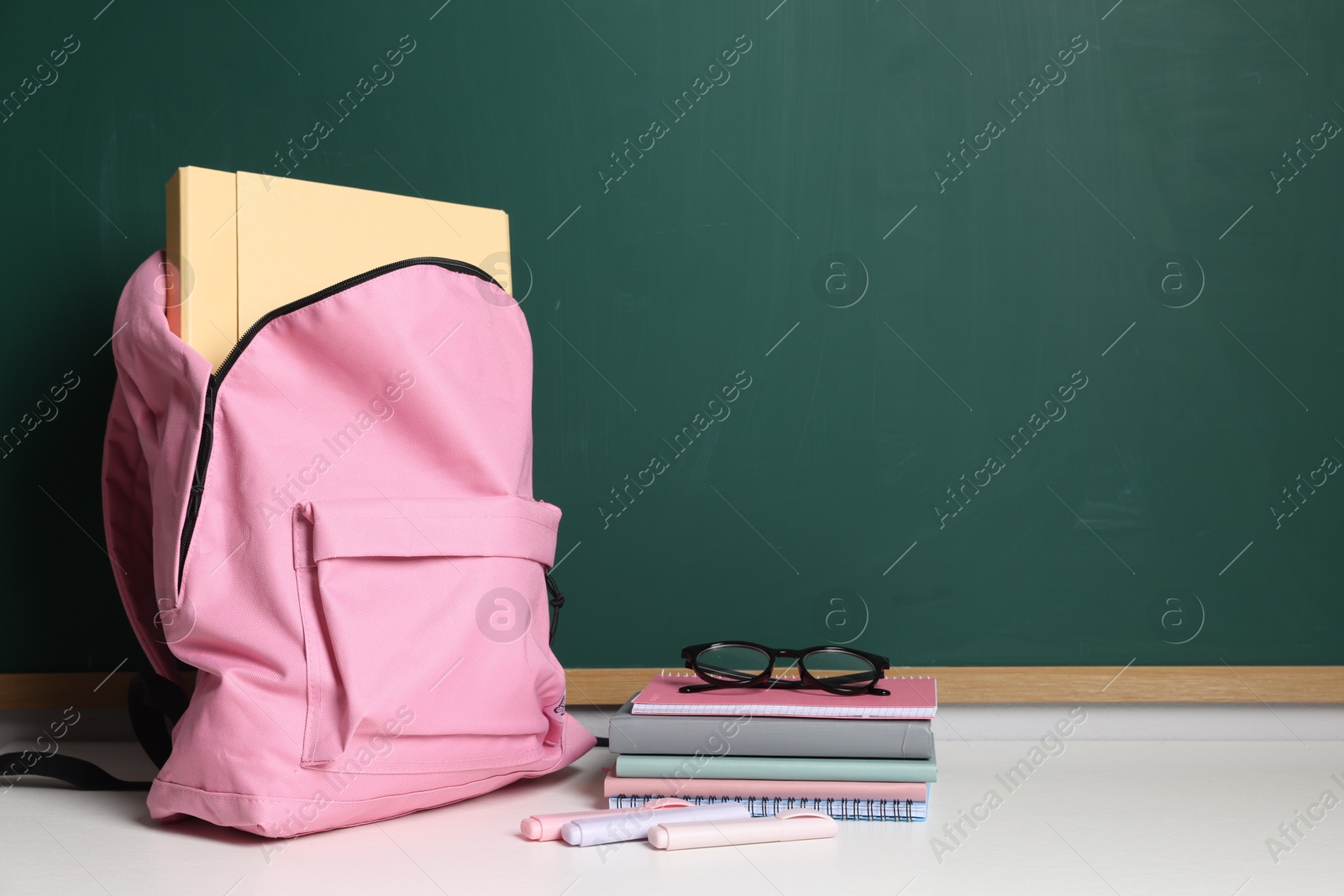 Blank green chalkboard, different stationery, backpack and glasses, space for text Photo of Blank green chalkboard, different stationery, backpack and glasses, space for text