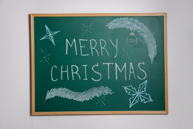 Photo of Phrase Merry Christmas and different drawings on green chalkboard