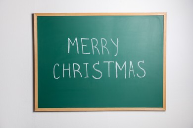 Photo of Green chalkboard with phrase Merry Christmas on wall