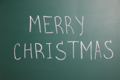 Photo of Phrase Merry Christmas on green chalkboard, closeup