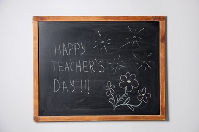 Photo of Phrase Happy Teacher’s Day with exclamation marks and drawings on blackboard