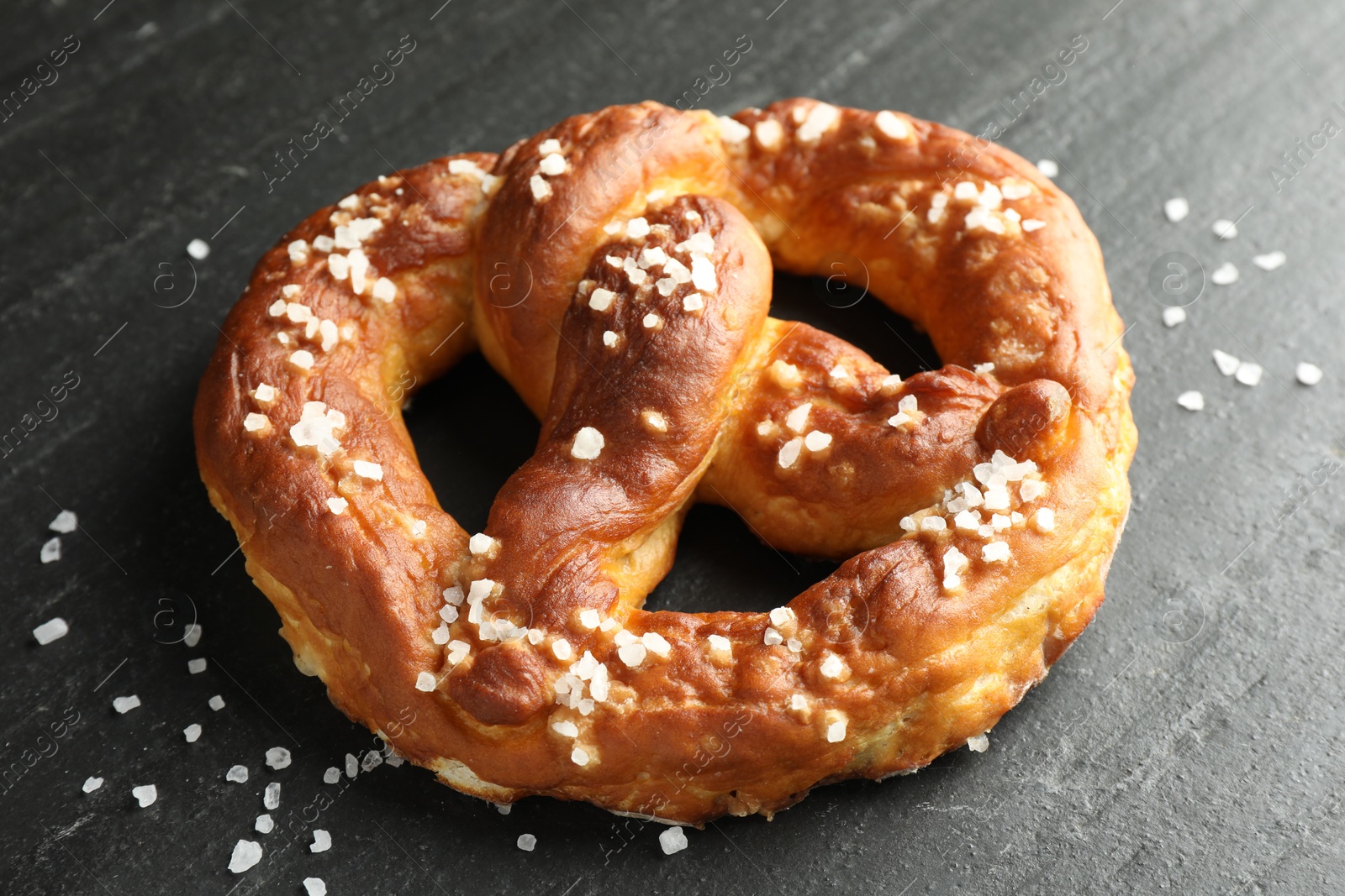 Tasty pretzel with salt on black table, closeup Photo of Tasty pretzel with salt on black table, closeup