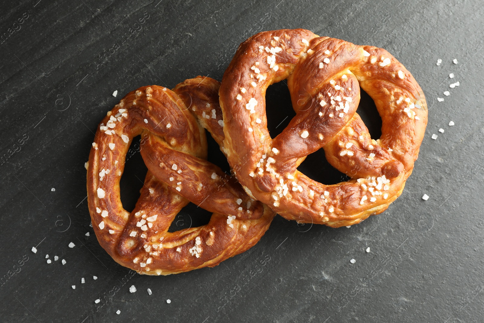 Tasty pretzels with salt on black table, flat lay Photo of Tasty pretzels with salt on black table, flat lay
