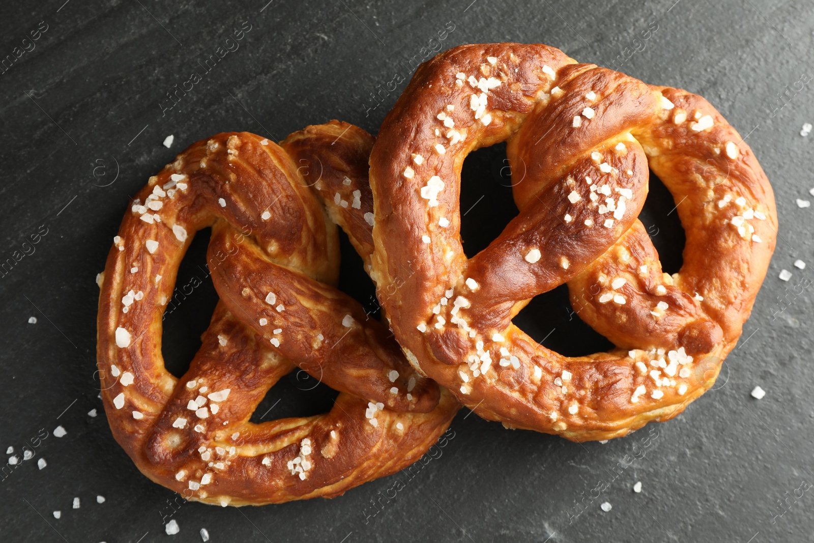 Tasty pretzels with salt on black table, flat lay Photo of Tasty pretzels with salt on black table, flat lay