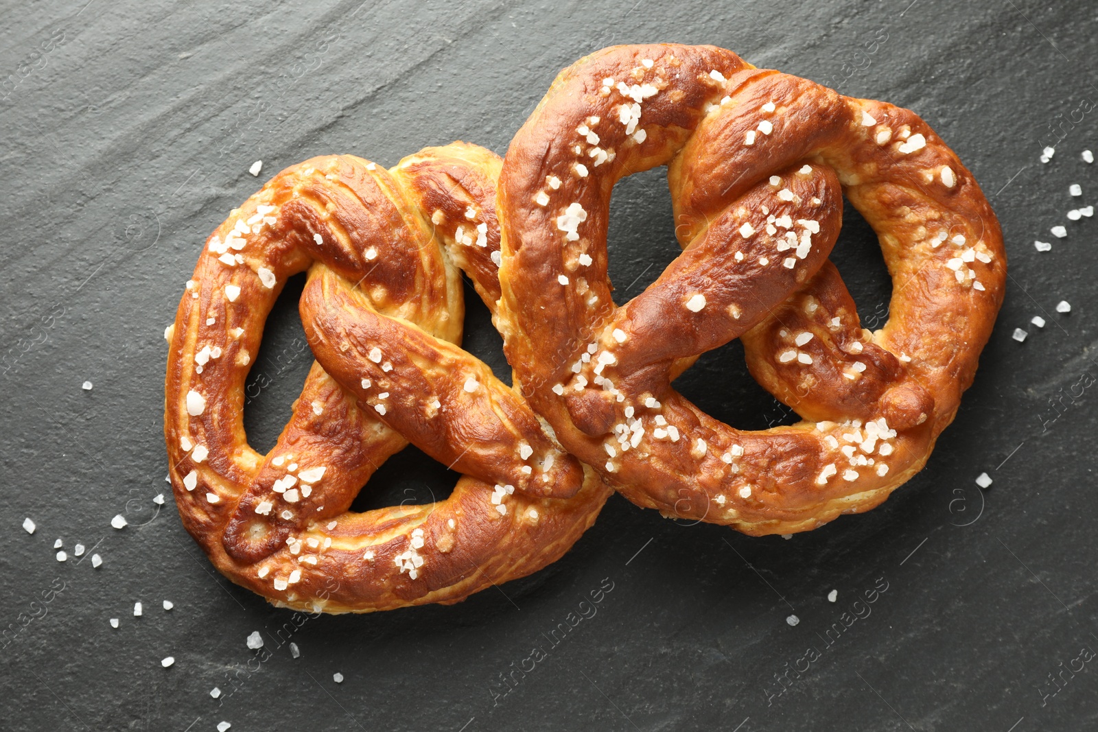 Tasty pretzels with salt on black table, flat lay Photo of Tasty pretzels with salt on black table, flat lay
