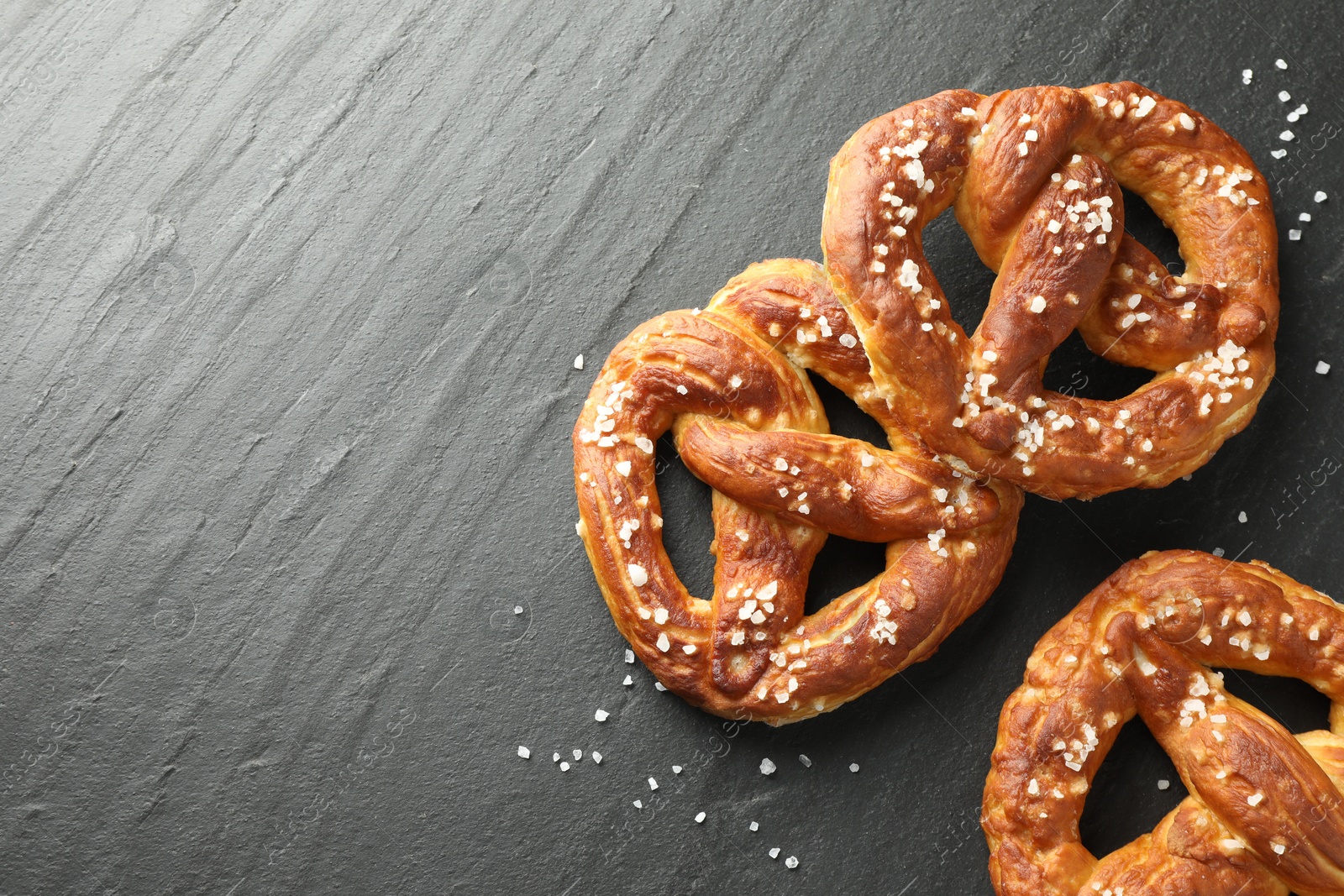 Tasty pretzels with salt on black table, flat lay. Space for text Photo of Tasty pretzels with salt on black table, flat lay. Space for text