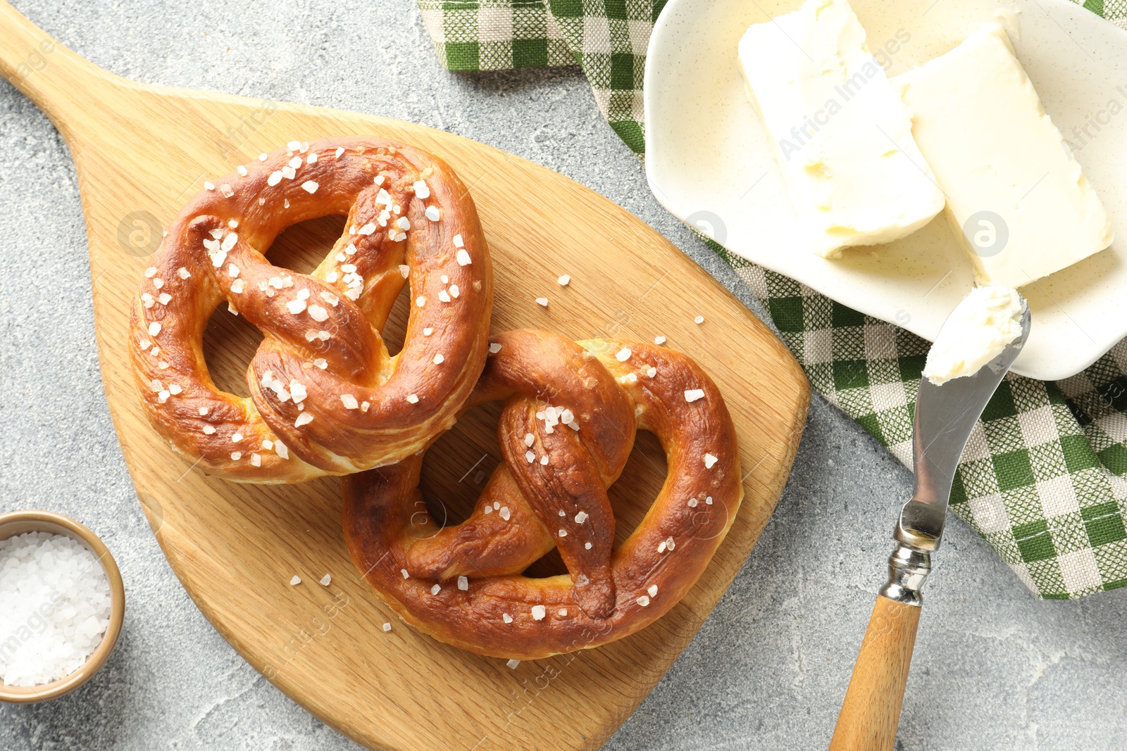 Tasty pretzels with salt and butter on light grey table, flat lay Photo of Tasty pretzels with salt and butter on light grey table, flat lay
