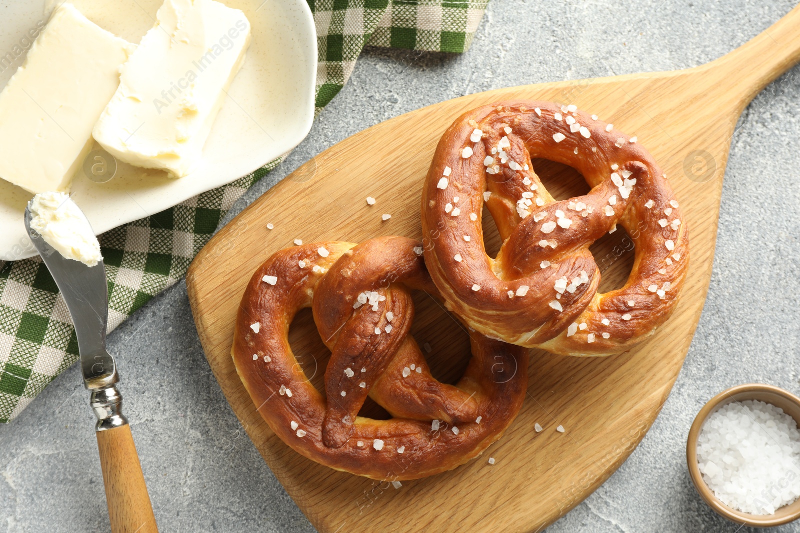 Tasty pretzels with salt and butter on light grey table, flat lay Photo of Tasty pretzels with salt and butter on light grey table, flat lay