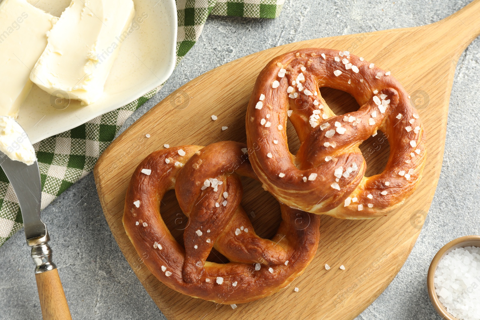 Tasty pretzels with salt and butter on light grey table, flat lay Photo of Tasty pretzels with salt and butter on light grey table, flat lay