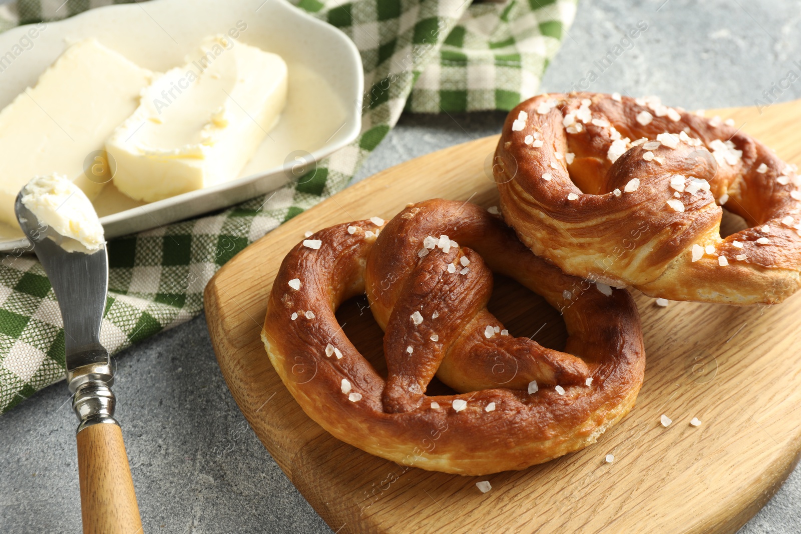 Tasty pretzels with salt and butter on light grey table, closeup Photo of Tasty pretzels with salt and butter on light grey table, closeup