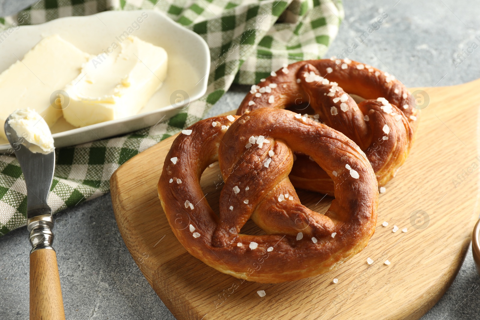 Tasty pretzels with salt and butter on light grey table, closeup Photo of Tasty pretzels with salt and butter on light grey table, closeup