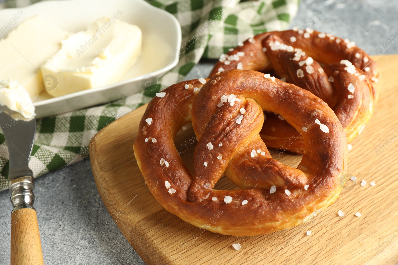 Tasty pretzels with salt and butter on light grey table, closeup Photo of Tasty pretzels with salt and butter on light grey table, closeup