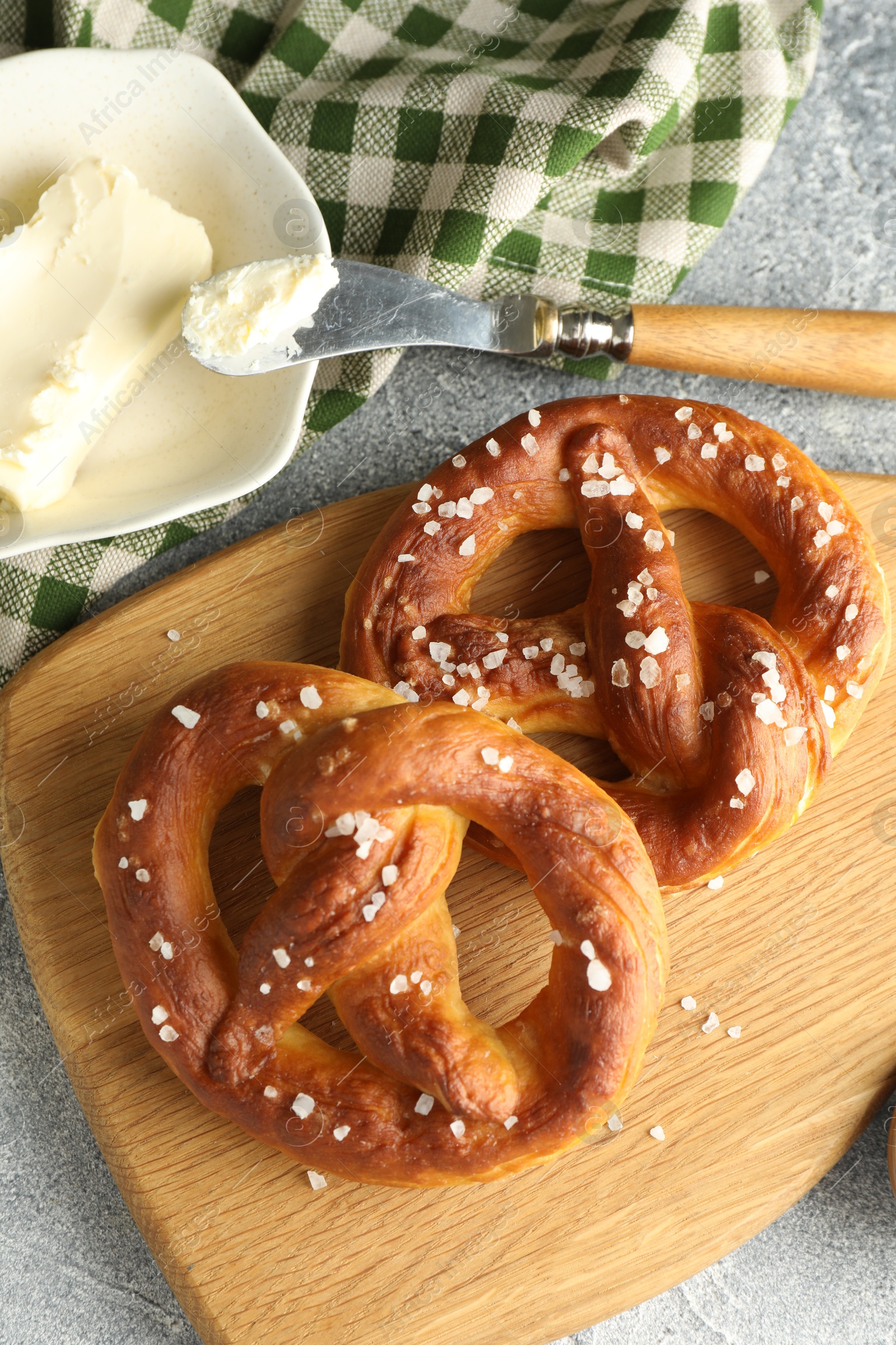 Tasty pretzels with salt and butter on light grey table, flat lay Photo of Tasty pretzels with salt and butter on light grey table, flat lay