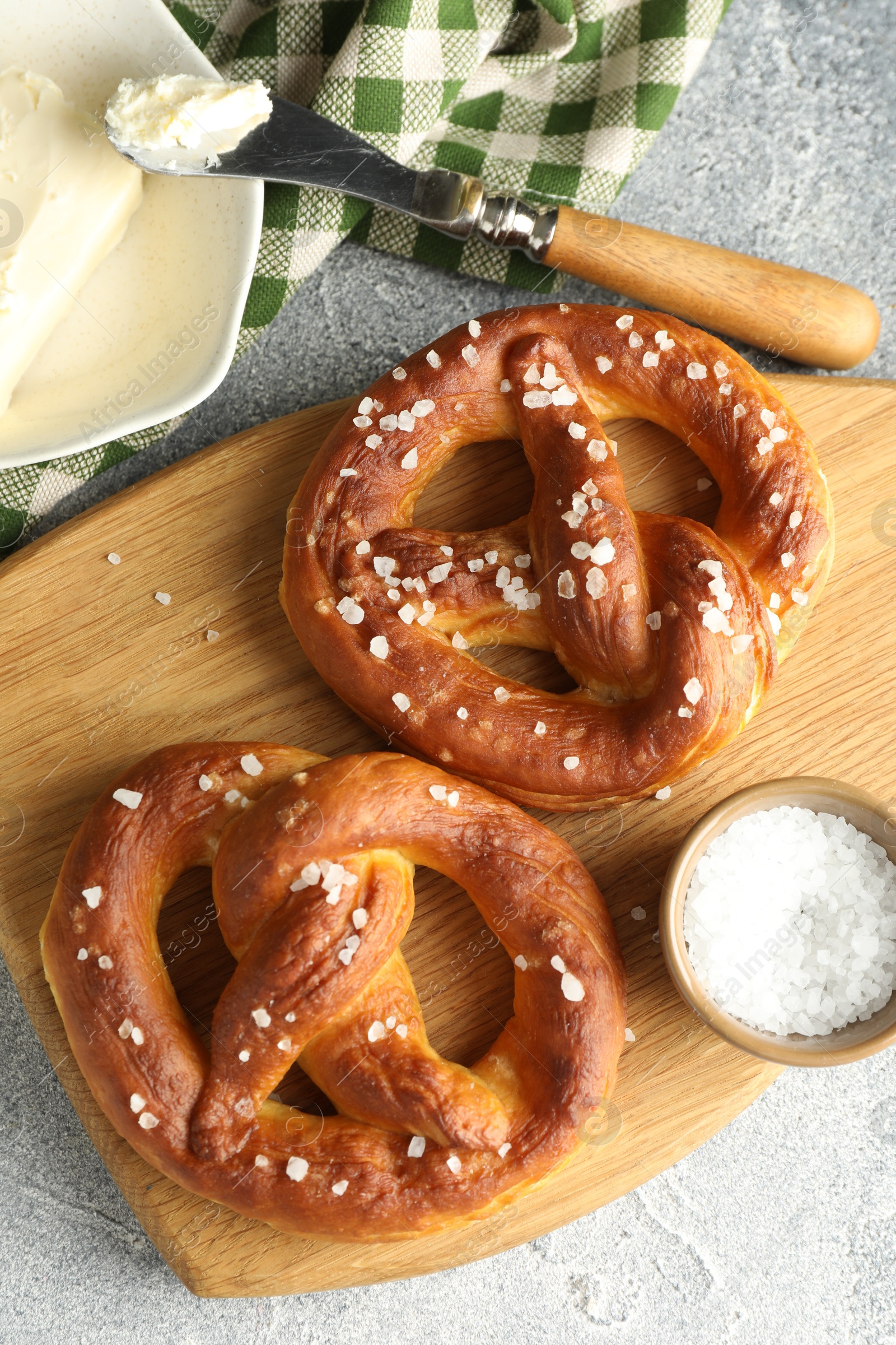 Tasty pretzels with salt and butter on light grey table, flat lay Photo of Tasty pretzels with salt and butter on light grey table, flat lay