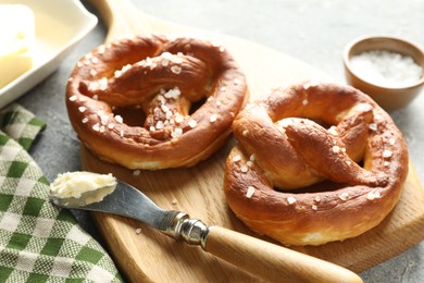 Photo of Tasty pretzels with salt and butter on table, closeup