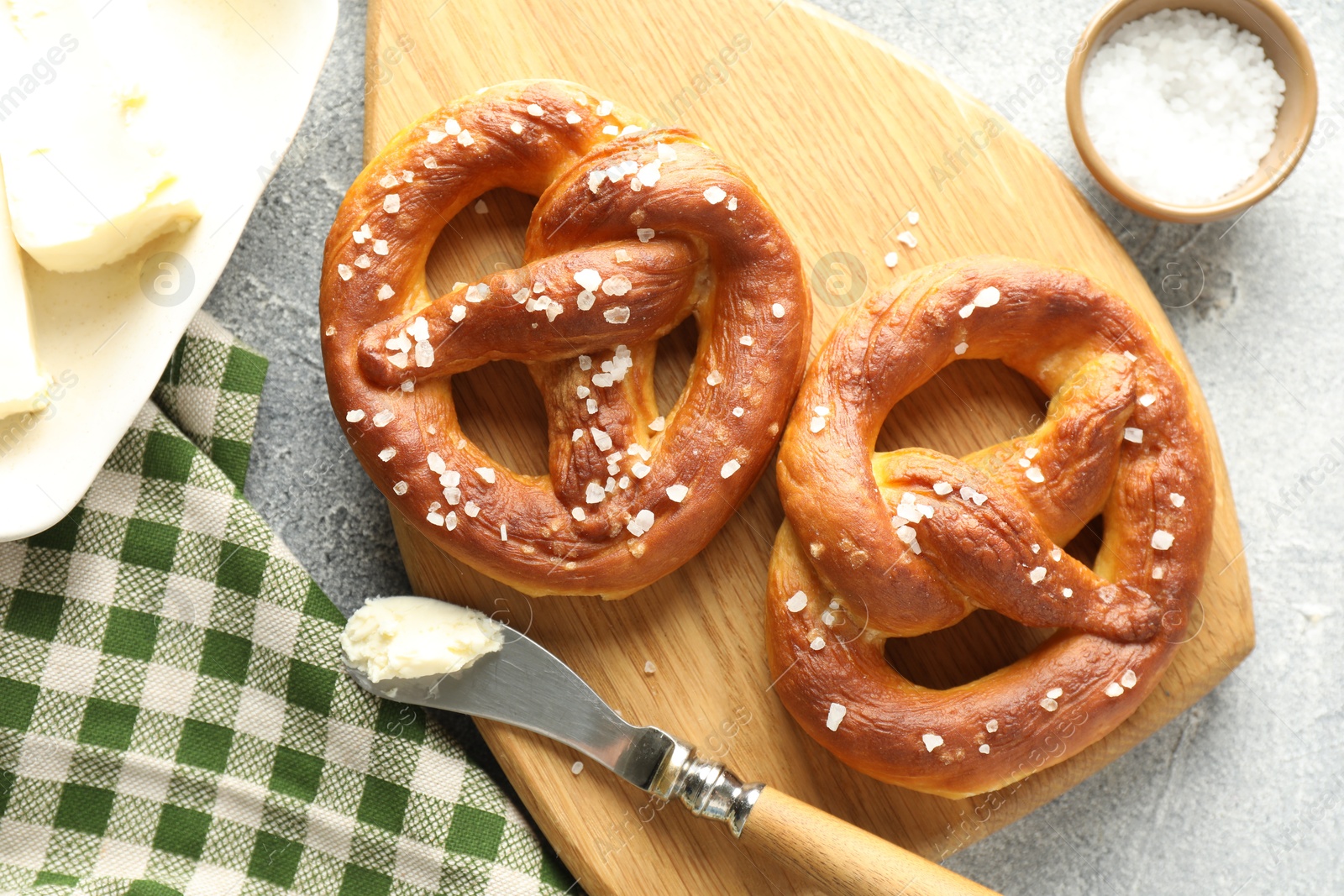 Tasty pretzels with salt and butter on light grey table, flat lay Photo of Tasty pretzels with salt and butter on light grey table, flat lay