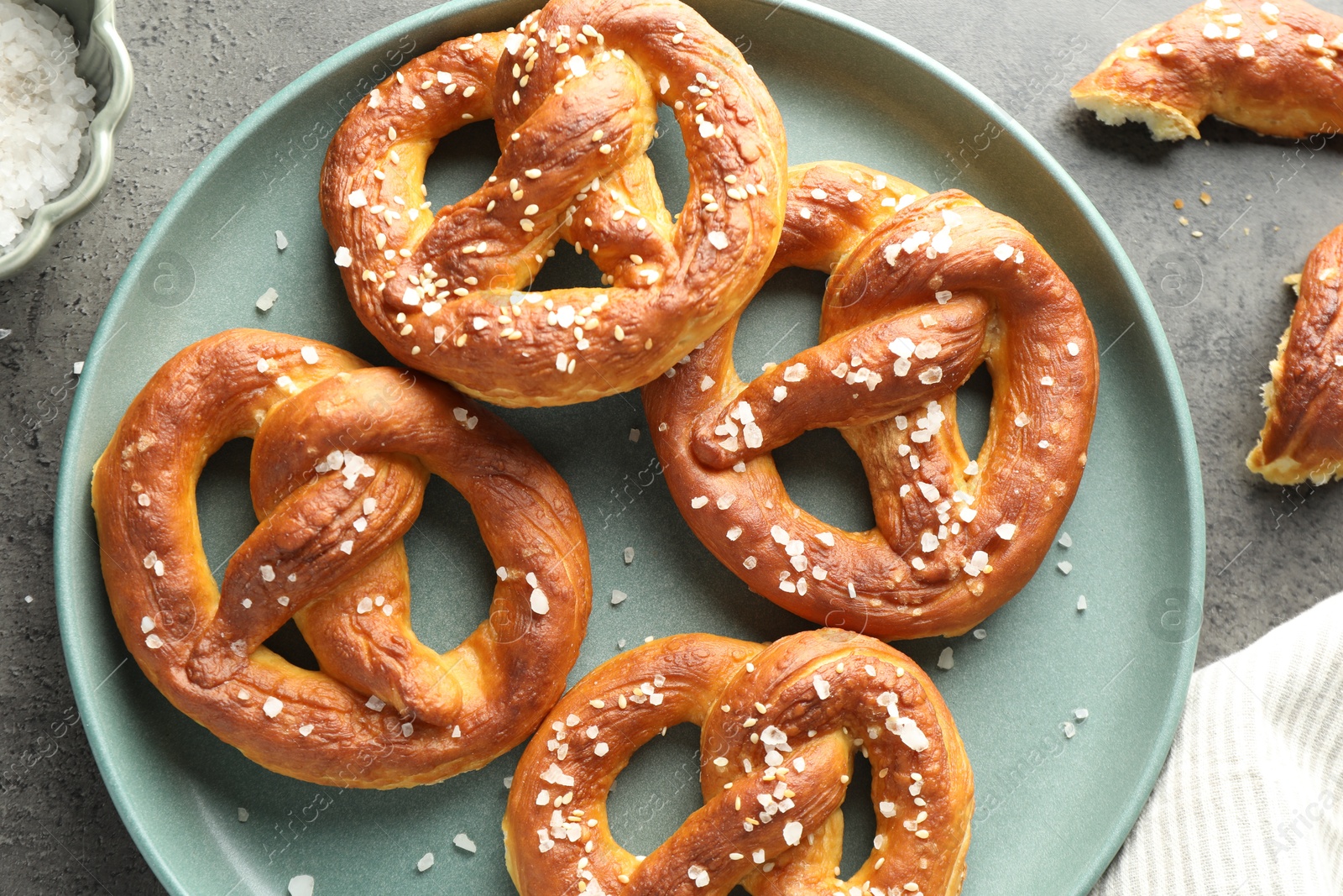 Tasty pretzels with salt on grey table, flat lay Photo of Tasty pretzels with salt on grey table, flat lay