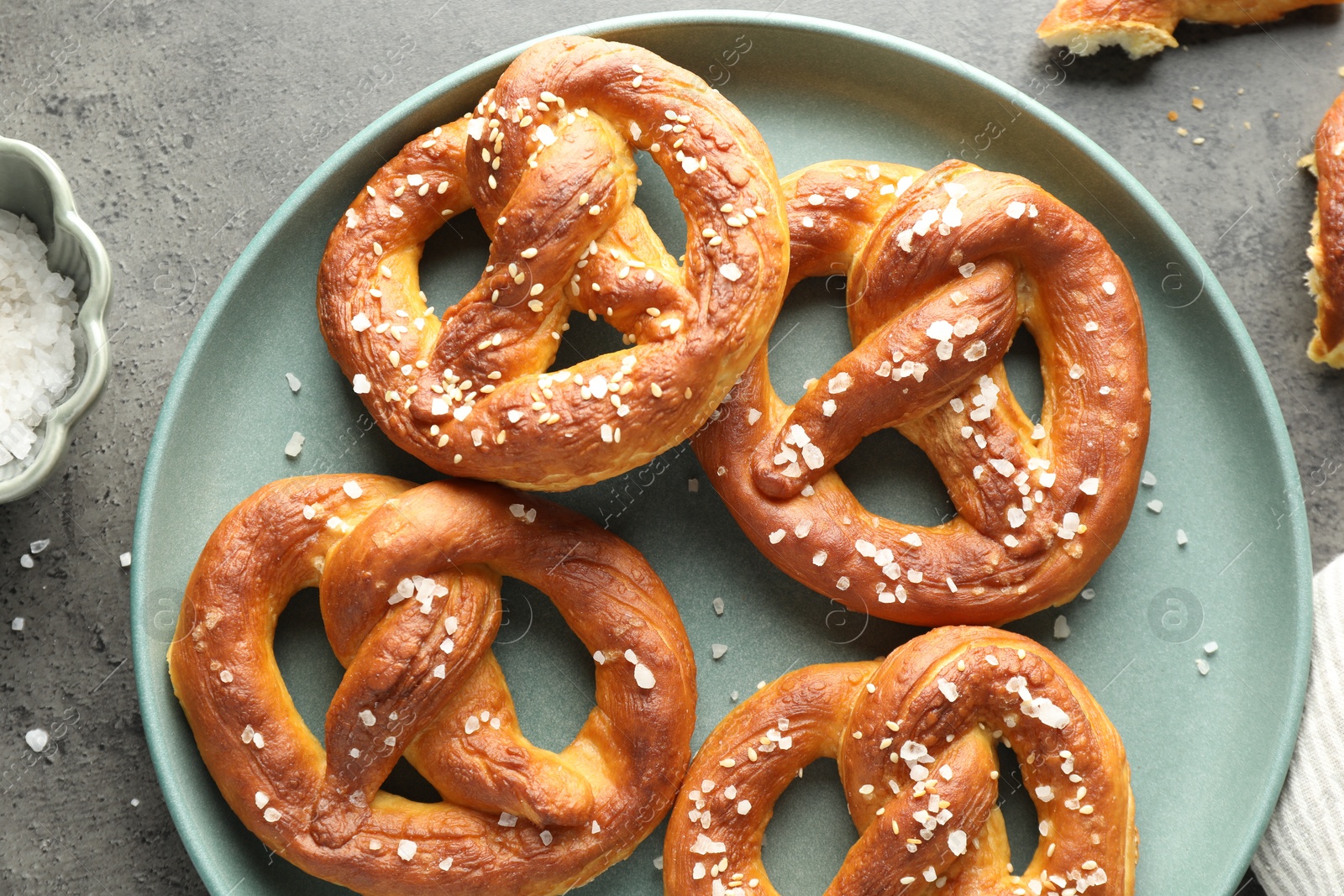 Tasty pretzels with salt on grey table, flat lay Photo of Tasty pretzels with salt on grey table, flat lay