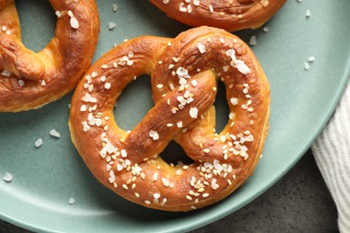 Photo of Tasty pretzels with salt on grey table, top view