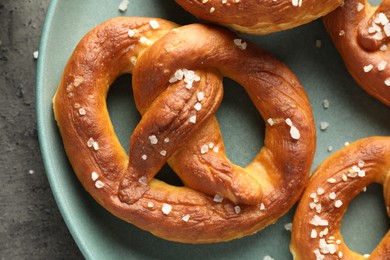 Photo of Tasty pretzels with salt on grey table, top view