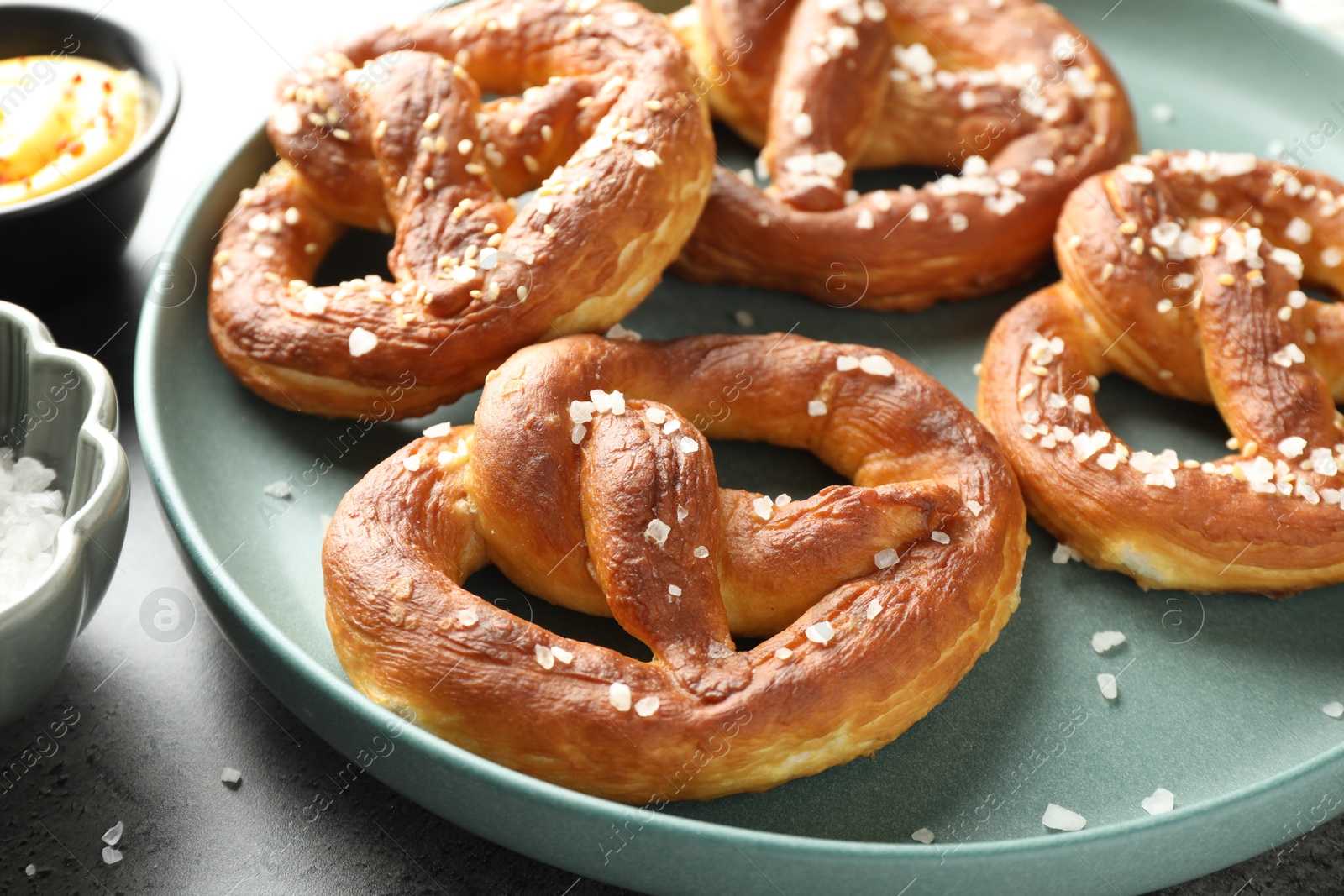 Tasty pretzels with salt and sauce on grey table, closeup Photo of Tasty pretzels with salt and sauce on grey table, closeup