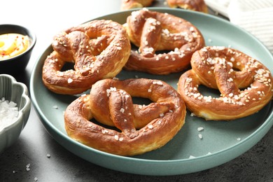 Photo of Tasty pretzels with salt and sauce on grey table, closeup