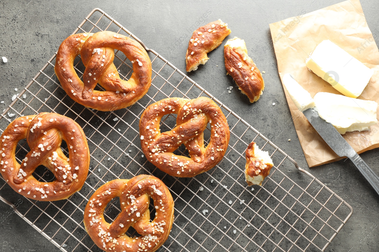 Tasty pretzels with salt and butter on grey table, flat lay Photo of Tasty pretzels with salt and butter on grey table, flat lay