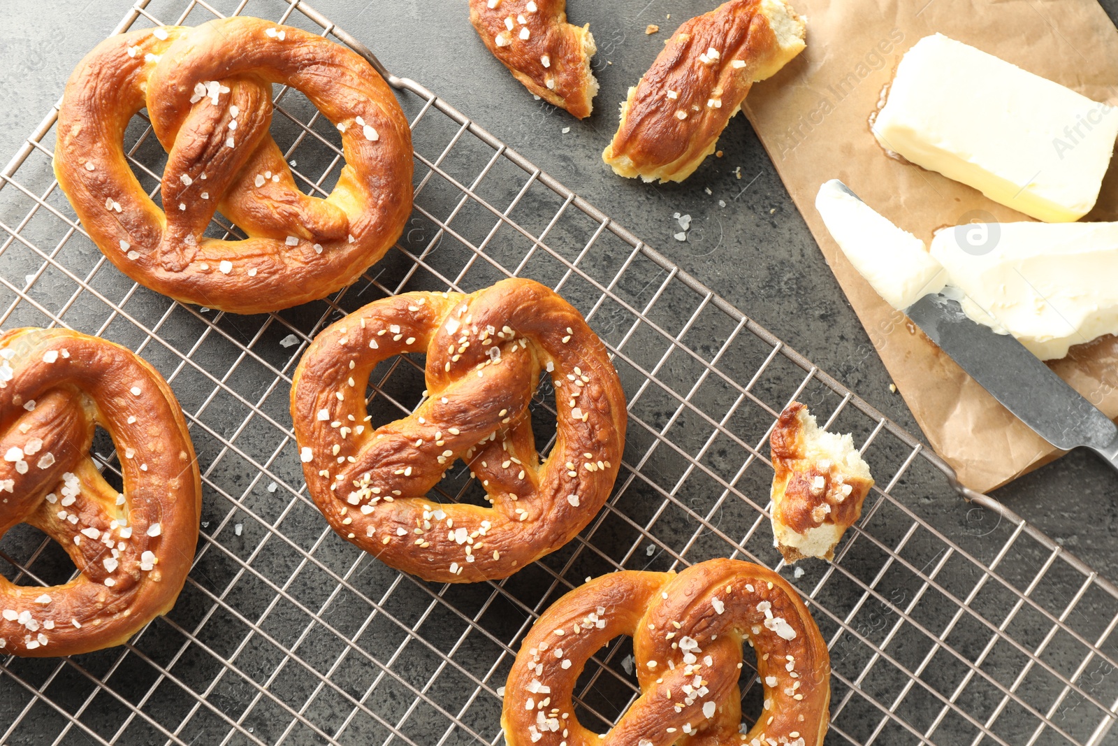 Tasty pretzels with salt and butter on grey table, flat lay Photo of Tasty pretzels with salt and butter on grey table, flat lay