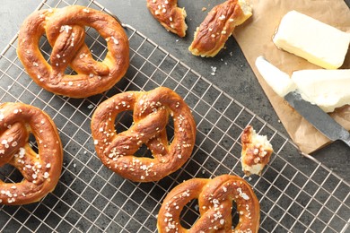 Photo of Tasty pretzels with salt and butter on grey table, flat lay