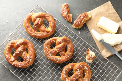 Photo of Tasty pretzels with salt and butter on grey table, flat lay