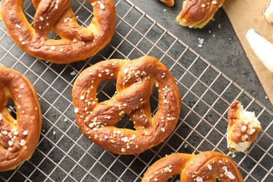 Photo of Tasty pretzels with salt and butter on grey table, flat lay