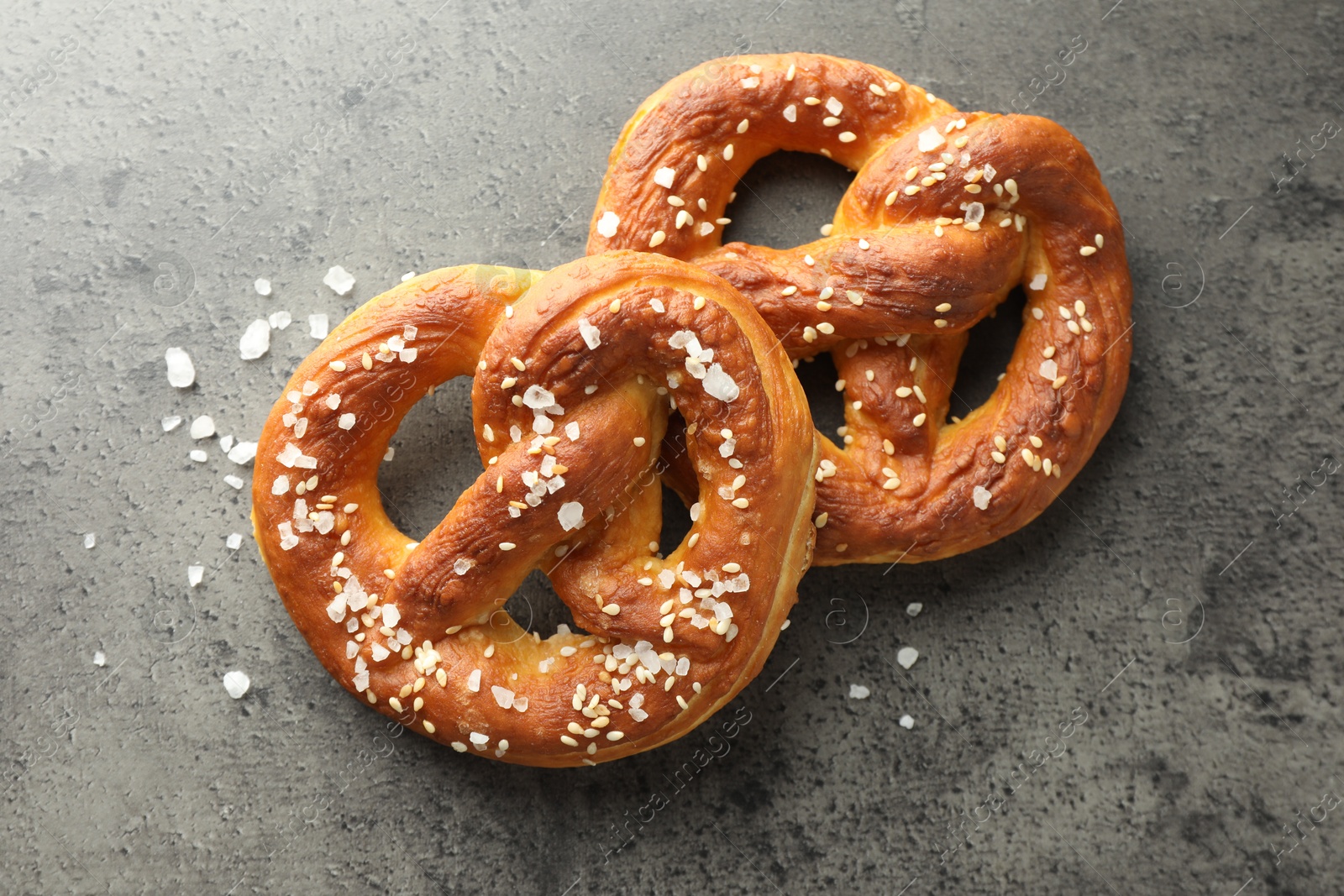 Tasty pretzels with salt on grey table, flat lay Photo of Tasty pretzels with salt on grey table, flat lay