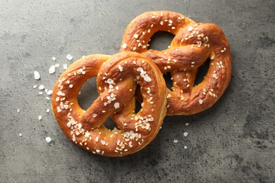 Photo of Tasty pretzels with salt on grey table, flat lay