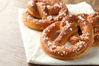 Photo of Tasty pretzels with salt on wooden table, closeup. Space for text