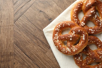 Photo of Tasty pretzels with salt on wooden table, flat lay. Space for text