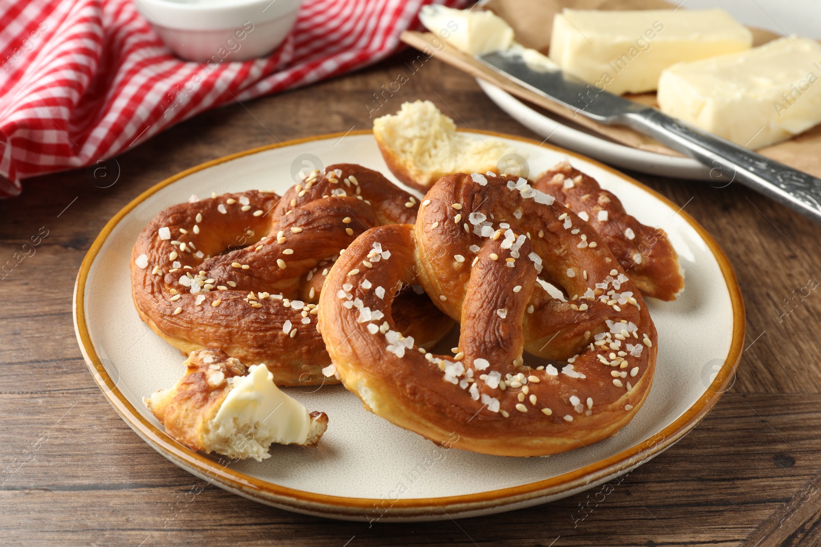 Tasty pretzels with salt and butter on wooden table, closeup Photo of Tasty pretzels with salt and butter on wooden table, closeup