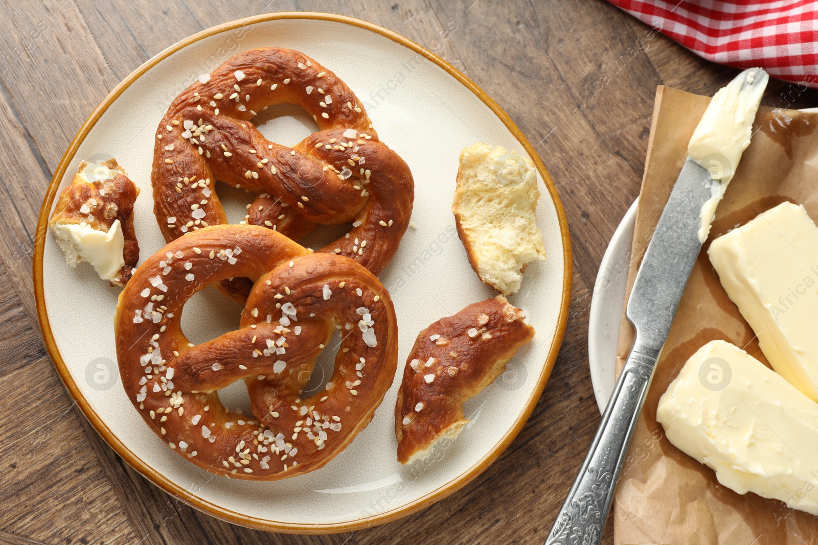 Tasty pretzels with salt and butter on wooden table, flat lay Photo of Tasty pretzels with salt and butter on wooden table, flat lay